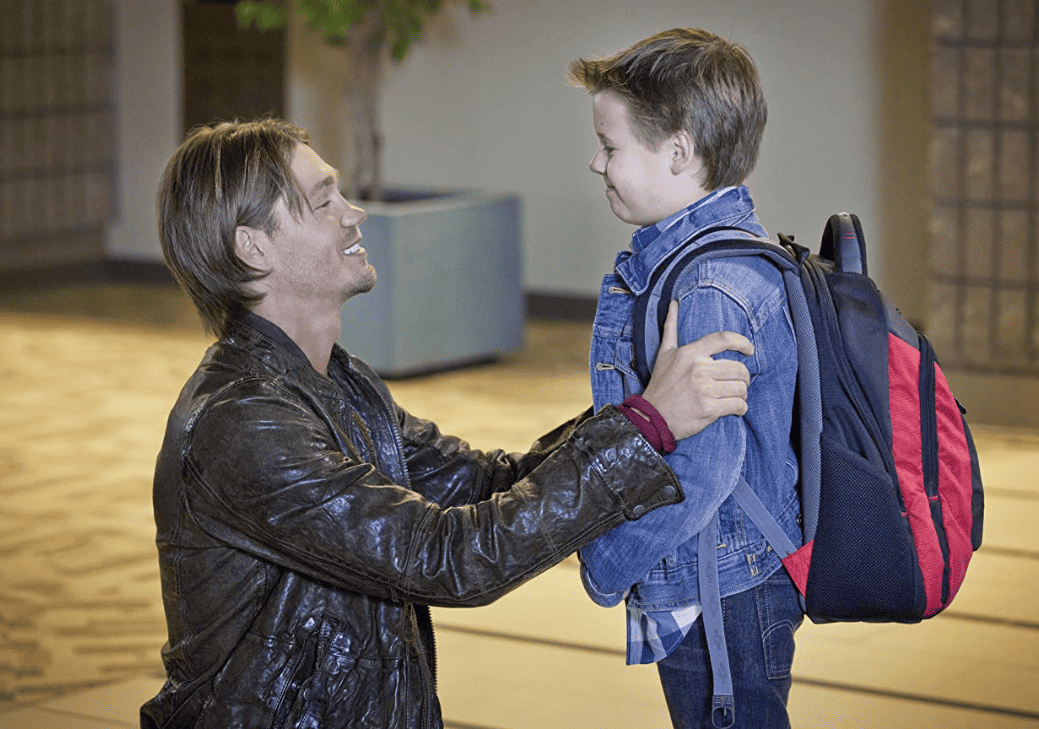 An uncle kneeling down and smiling at his young nephew in this image from Tollin/Robbins Productions/Warner Bros. Television