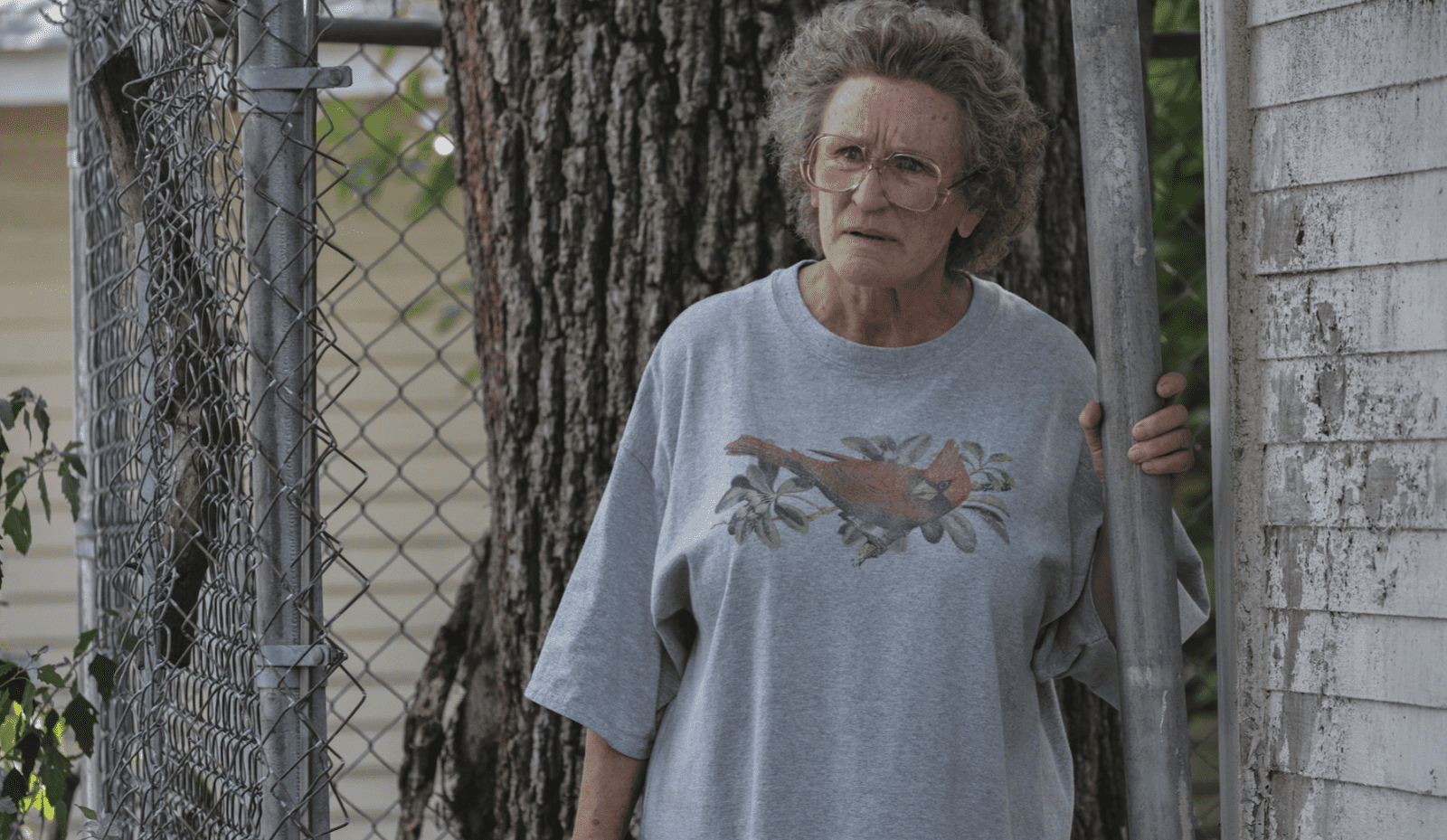  An older woman with thick eyeglasses and curly hair stares in disbelief.