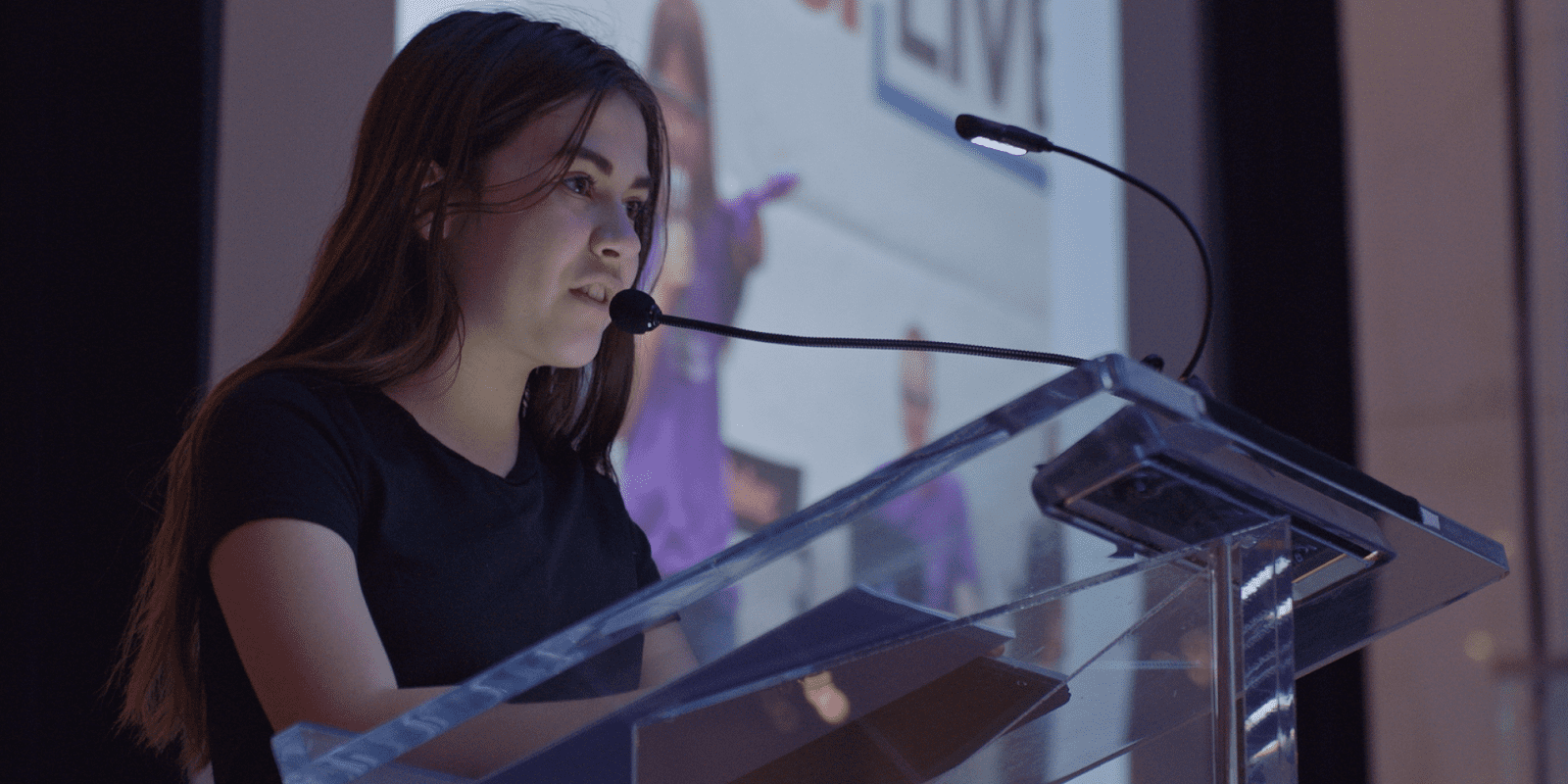 A young girl stands before a podium and confidently addresses her audience. 