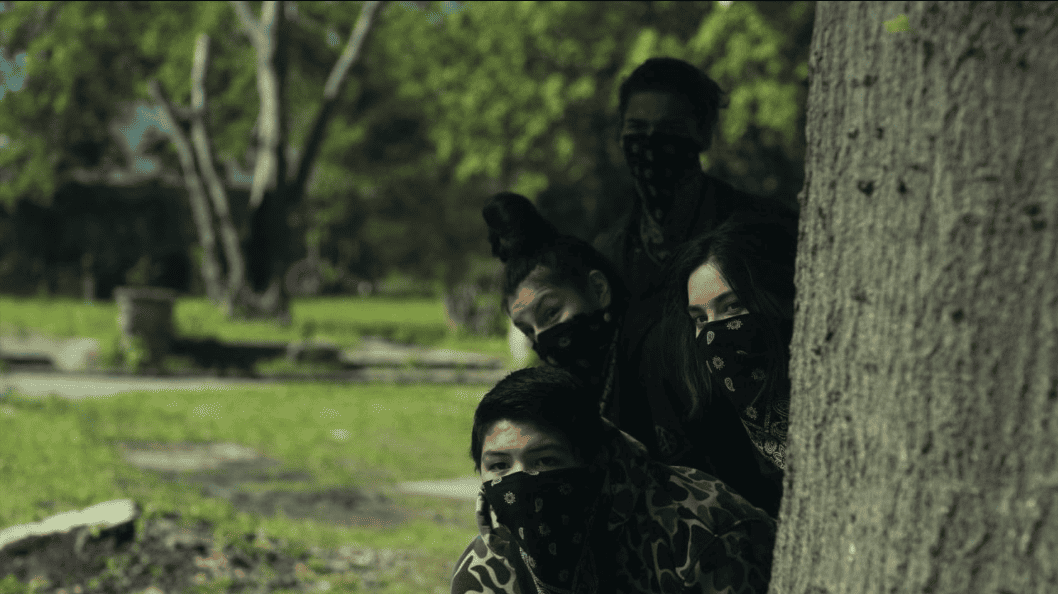 Four teenagers lean around a tree with bandanas covering half their faces in this image from FX Productions